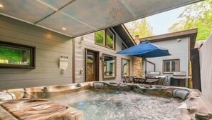 Un espace avec un bain à remous, un mur en pierre, une terrasse en bois et un parasol bleu.