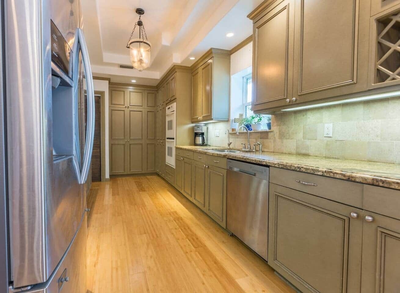 A kitchen with stainless steel appliances, wooden cabinets, and a granite countertop.