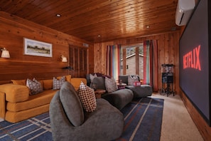 Cozy cabin-style theater room with projector screen and plush seating - The Painted Turtle: Lakefront, Hot Tub, Sauna, Theater, Game Room, Playset (Nisswa)