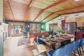A spacious dining area with a wooden ceiling, a large table set for six, and a kitchen with modern appliances. - The Painted Turtle: Lakefront, Hot Tub, Sauna, Theater, Game Room, Playset (Nisswa)