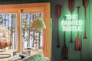 A room with a large window, a hanging lamp, and wooden paddles on the wall. - The Painted Turtle: Lakefront, Hot Tub, Sauna, Theater, Game Room, Playset (Nisswa)