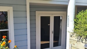 A house with a covered porch, a sliding glass door, and a wooden deck. - Fantail studio walk to town (Napier)