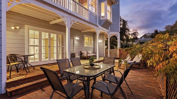 A two-story house with a covered patio area featuring a table and chairs. - Fantail studio walk to town (Napier)