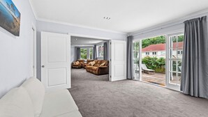 A spacious living room with a large sofa set, a white couch, and a sliding glass door leading to a patio. - Fantail studio walk to town (Napier)