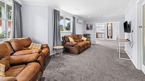 A spacious living room with two leather sofas, a coffee table, and a television. - Fantail studio walk to town (Napier)