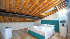 Ein Schlafzimmer mit einem Bett, einem Heizgerät, einem türkisblauen Kopfteil und einem kleinen weißen Schrank.