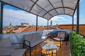 A covered outdoor seating area with a view of the cityscape, including a clock tower. - The House of Verona (Verona)