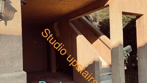 A building entrance with a staircase leading to an upper level, labeled "Studio upstairs" and "Renter parking here".