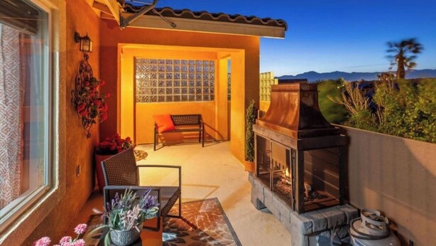 A cozy outdoor patio with a fireplace, a seating area, and a view of the mountains.