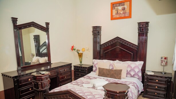 A bedroom with a large bed, a dresser, a vanity, and a mirror. - Casa con Encanto Centro Mazatlan 4 Rec (Mazatlán)