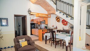 A dining area with a table set for four, a brown sofa, and a kitchen in the background. - Casa con Encanto Centro Mazatlan 4 Rec (Mazatlán)