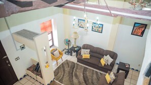 A living room with a brown sofa, a yellow armchair, a small table, and a rug. - Casa con Encanto Centro Mazatlan 4 Rec (Mazatlán)