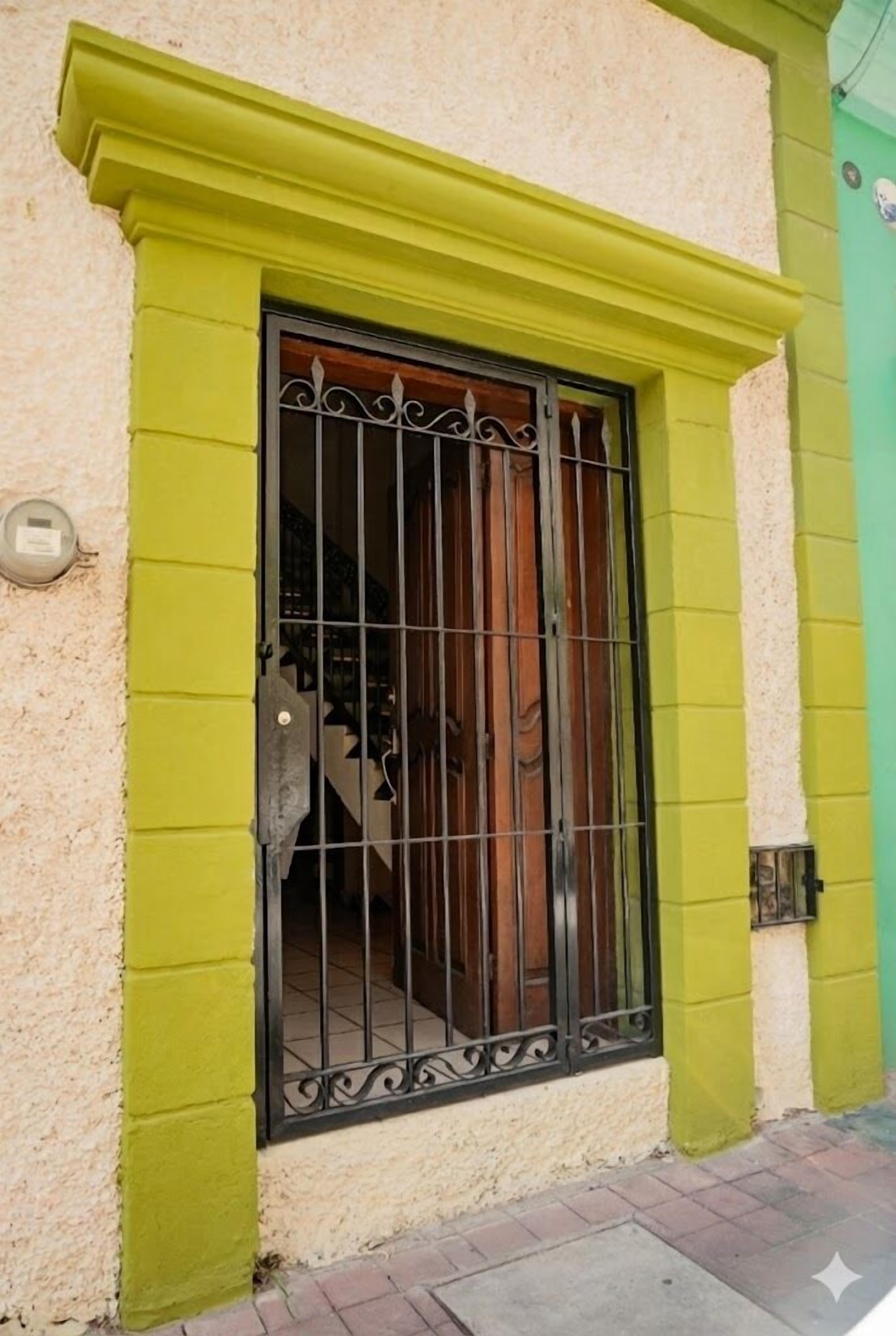 Un edificio con una puerta verde y un portón de metal.