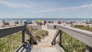 A wooden boardwalk leading to a sandy beach with umbrellas and people. - Oceans 211 is a colorful newly renovated suite in the popular Oceans Reef resort (Myrtle Beach)