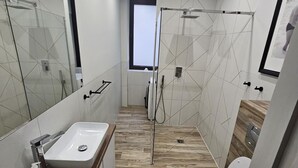 A modern bathroom with a wooden floor, a white sink, a glass shower enclosure, and a toilet. - Gdynia City Center 2 by Grand Apartments (Gdynia)