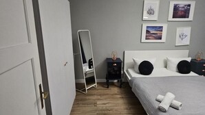 A bedroom with a bed, bedside tables, a mirror, and framed pictures on the wall. - Gdynia City Center 2 by Grand Apartments (Gdynia)