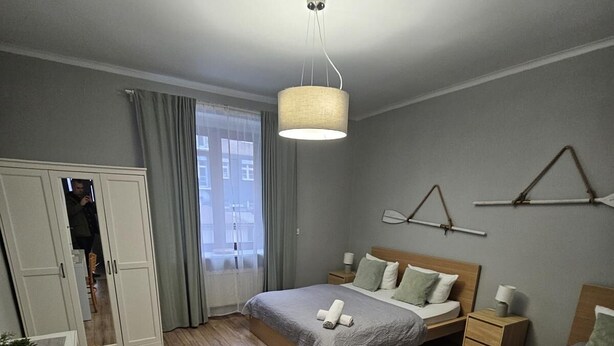 A hotel room with a wooden floor, two beds, a desk, and a wardrobe. - Gdynia City Center 2 by Grand Apartments (Gdynia)