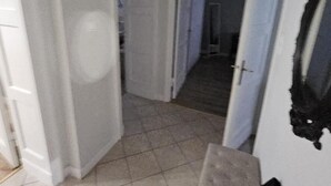 A hallway with a tiled floor, white walls, and a door leading to another room. - Gdynia City Center 2 by Grand Apartments (Gdynia)