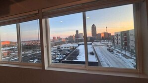 A view through a window with multiple panes, showing a cityscape with buildings and a parking lot.