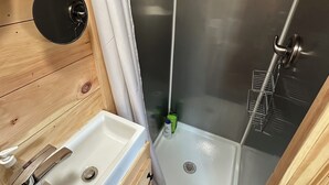 Et moderne badeværelse med en trækommode, vask og brusekabine.