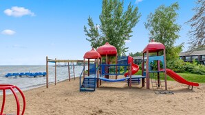 Un'area giochi in riva al mare, con scivolo e strutture per arrampicarsi, con vista su un'area d'acqua.