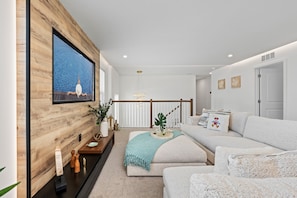 Ein modernes Wohnzimmer mit einer großen Holzwand, einer Sofagarnitur, einem Couchtisch und einer Treppe im Hintergrund.