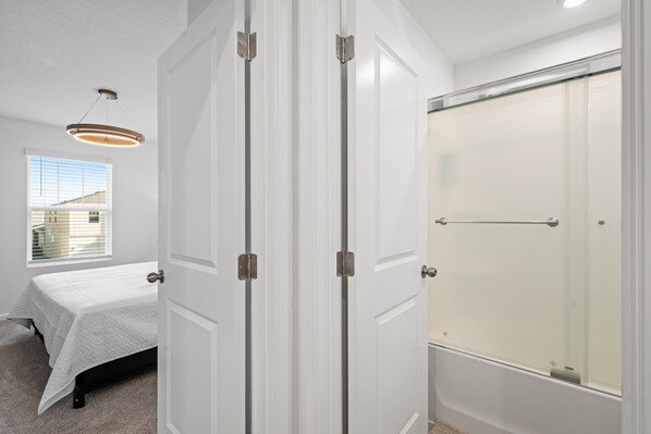 A bedroom with a bed, a window, and a shower. - Light Welcoming Fun Resort Home Sleeps 20 (Kissimmee)