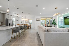 Una cocina moderna con una isla central, taburetes de bar e iluminación colgante.