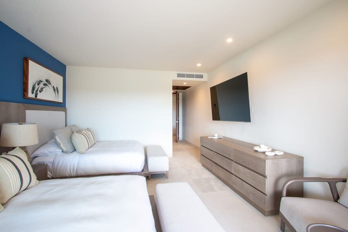 A modern hotel room with a large bed, a bedside table, a dresser, and a flat-screen TV mounted on the wall.