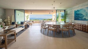 Un vaste espace de vie comprenant une table à manger ronde, des sièges confortables et une grande fenêtre offrant une vue panoramique.