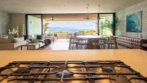 Une cuisine moderne dotée d’un grand îlot central, d’un coin repas offrant une vue agréable et d’un espace de vie comprenant un canapé et une table basse.