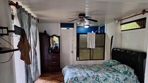 A bedroom with a bed, a ceiling fan, a wardrobe, and a window with curtains. - Escape to Your Private Costa Rican Jungle Retreat (Atenas)