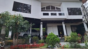 A two-story house with a covered porch and a car parked in the driveway. - Escape to Your Private Costa Rican Jungle Retreat (Atenas)