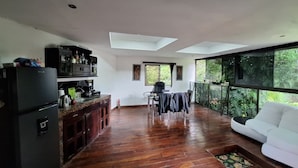 A spacious living area with a kitchen, dining table, and a white sofa. - Escape to Your Private Costa Rican Jungle Retreat (Atenas)