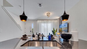 A modern kitchen with a central island, stainless steel sink, and pendant lighting. - 3BR Home Near Disney w/ Office & Fun Corner (Kissimmee)