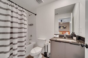 A modern bathroom with a shower curtain, toilet, sink, and mirror. - 3BR Home Near Disney w/ Office & Fun Corner (Kissimmee)