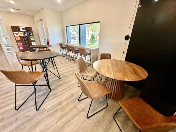 A modern meeting room with round tables and chairs, large windows, and a wooden floor. - 3BR Home Near Disney w/ Office & Fun Corner (Kissimmee)