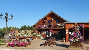 Eine Holzhütte mit Balkon, geschmückt mit Blumen, Sitzgelegenheit im Freien und einem Schild mit der Aufschrift 'Crazy Horse Saloon'.