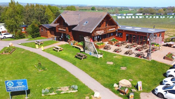 Ein Holzgebäude mit Balkon, umgeben von einer Rasenfläche mit Picknicktischen und einem Schild für Felmoor Holiday Park.
