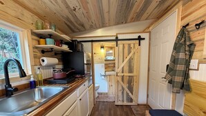 Een kleine keuken met houten kastjes, een spoelbak en een kookplaat.