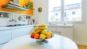 Een moderne keuken met witte kasten, een roestvrijstalen afzuigkap en een raam met uitzicht op gebouwen.