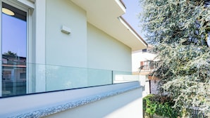 Een modern gebouw met een glazen balkon, witte muren en een klein raam.