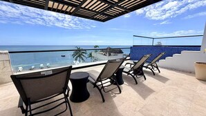 Una terrazza con vista sull'oceano, con un'area bar, sedie e un tavolino.