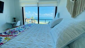 Una camera da letto con un letto grande, vista sulla spiaggia, una piccola scrivania e una sedia.