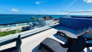 Un balcone con vista sull'oceano, una piscina e un'area salotto all'aperto.