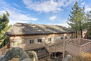Une cabane en bois à deux étages, dotée d’un balcon, entourée de gros rochers et de pins.