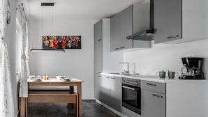 Una cuina moderna amb armaris grisos, una taula de dinar de fusta, una cafetera i un quadre decoratiu.