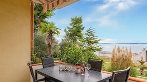 A terrace with a table set for two, overlooking a body of water and a distant landscape. - Luxurious apartment in Vir with house sea view (Vir)