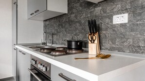 A modern kitchen with a granite backsplash, stainless steel appliances, and a knife block on the countertop. - Luxurious apartment in Vir with house sea view (Vir)