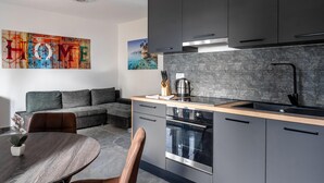 Une cuisine moderne avec des meubles de couleur sombre, un pare-feu en pierre et un four encastré.
